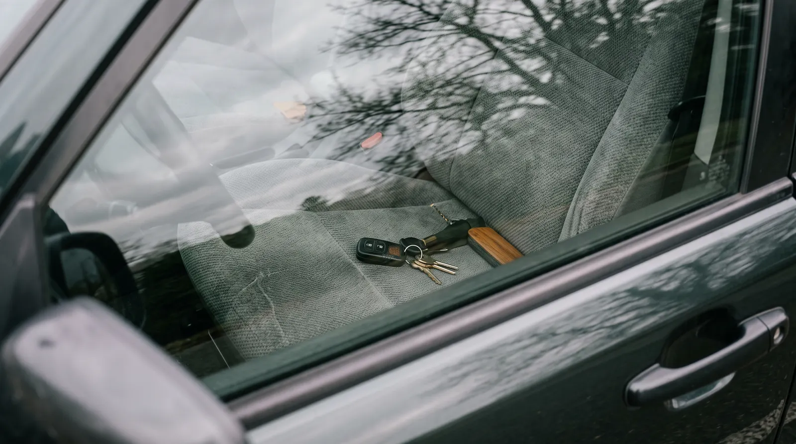 Car keys resting on a driver seat seen through a closed window